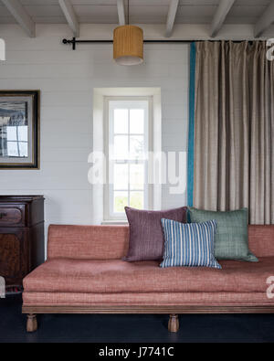 Coussins assortis sur canapé avec rideaux tirés pour un maximum de lumière naturelle Banque D'Images