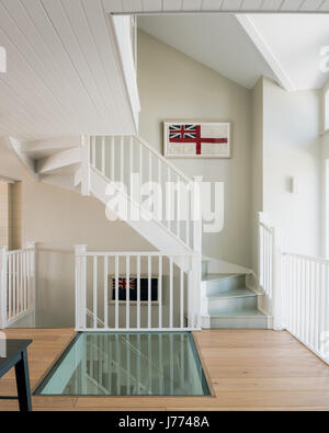 Sol en verre sur la première histoire palier avec pans de vieux drapeaux britanniques le long de l'escalier. Les murs sont peints en gris Quill par Sanderson. Banque D'Images