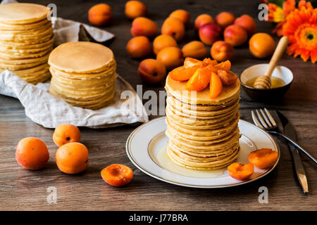 Maison de Stackes crêpes américaines avec du miel et d'abricot sur fond de bois. Banque D'Images