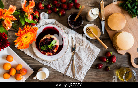 Vue supérieure de la pile de crêpes américaines faites maison avec la confiture et les fraises sur fond de bois. Banque D'Images