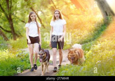 Deux smiling teenage girls walking avec ses chiens dans la région de Spring Park Banque D'Images