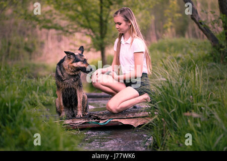 Adolescente en chemise blanche avec son chien assis près du ruisseau dans le parc. Les tons de couleurs chaudes de droit Banque D'Images