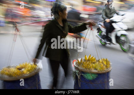 Les femmes avec un pôle transport walking thru le marché de Hanoi, Vietnam Banque D'Images