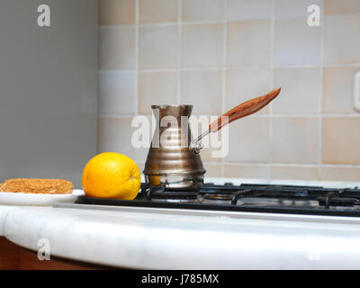 Pot de café turc de cuivre sur une cuisinière à côté d'un brownie et citron Banque D'Images