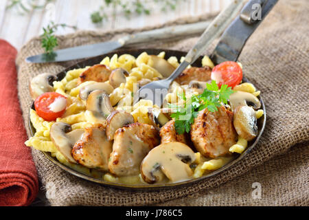 Médaillons de filet de porc frit avec spaetzle Souabe (Schwabenpfandl Schwabentopf ou soi-disant ) et champignons sauce crème servi dans une poêle Banque D'Images