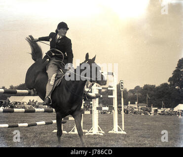 Années 1950, historiques, une femelle equestrian rider saute par-dessus une clôture à trois barres les Bucks County Show Ground à Weedon Park. Banque D'Images