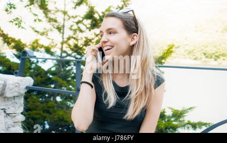 Femme avec téléphone, parle et sourire Banque D'Images