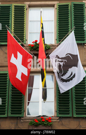 Les drapeaux de la Suisse et de l'Interlaken sur un immeuble situé à Interlaken, en Suisse. La municipalité est une passerelle vers les Alpes. Banque D'Images
