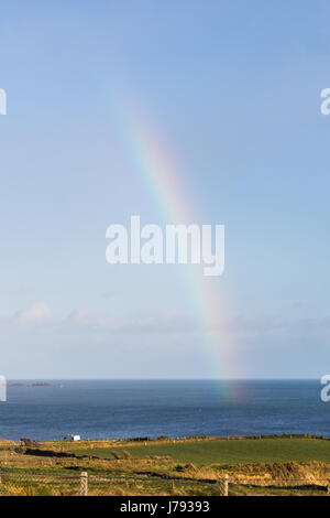 Un arc-en-ciel en milieu rural campagne irlandaise se terminant dans la mer d'Irlande Banque D'Images