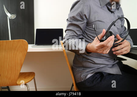 L'homme à l'aide de VOIP casque avec ordinateur portable et tablette numérique comme la communication concept,elle,support centre d'appels et customer service help desk Banque D'Images