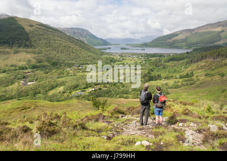 Village de Glencoe et le Loch Leven - deux randonneurs à la recherche au niveau de la vue de Glencoe village depuis le sentier menant jusqu'au Pap of Glencoe, Ecosse Banque D'Images