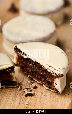 Libre de certains argentine-uruguayen alfajores rempli de dulce de leche et recouverts d'une couche blanche sur une planche en bois, sur un onglet rustique Banque D'Images