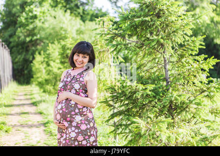 Femme enceinte posant dans le parc d'été. Banque D'Images