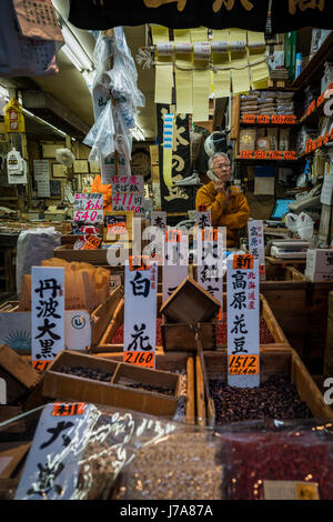 Un commerçant dans un bean shop dans le marché de Tsukiji est au téléphone. La boutique est petite et exiguë mais dynamique avec la couleur. Banque D'Images