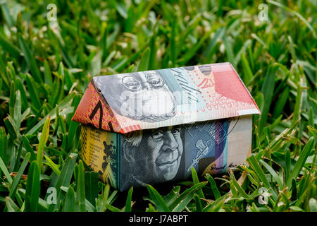 Maison Origami fait avec des notes d'Australie sitting on grass Banque D'Images