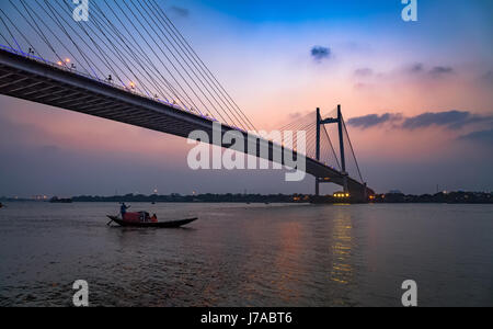 Vidyasagar setu bridge au crépuscule avec un bateau en bois sur la rivière Hooghly. Banque D'Images