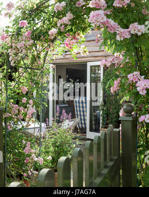 Vue à travers l'arche à la rose de jardin chêne-clad house extension avec fenêtres à la française Banque D'Images