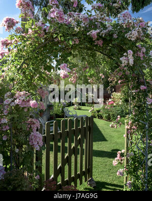 La porte de piquetage sous arch rose donnant sur charmant jardin clos anglais Banque D'Images