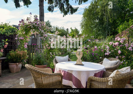 Fauteuils en osier autour de déposer en anglais jardin clos avec passage de rose Banque D'Images