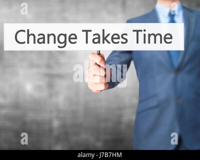Le changement nécessite du temps - Businessman hand holding sign. Le commerce, la technologie, internet concept. Stock Photo Banque D'Images