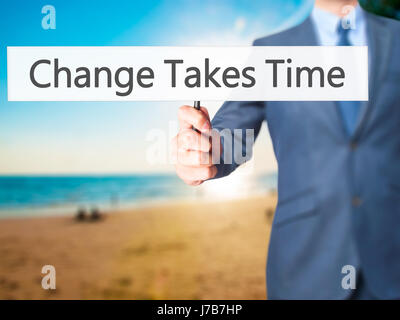 Le changement nécessite du temps - Businessman hand holding sign. Le commerce, la technologie, internet concept. Stock Photo Banque D'Images
