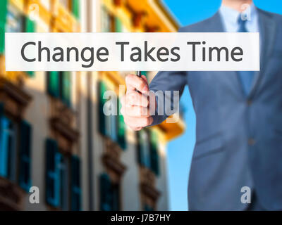 Le changement nécessite du temps - Businessman hand holding sign. Le commerce, la technologie, internet concept. Stock Photo Banque D'Images