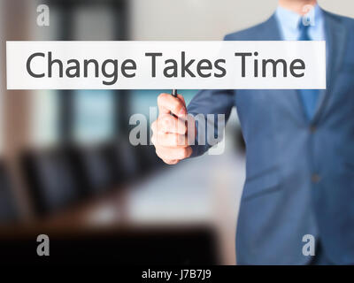 Le changement nécessite du temps - Businessman hand holding sign. Le commerce, la technologie, internet concept. Stock Photo Banque D'Images