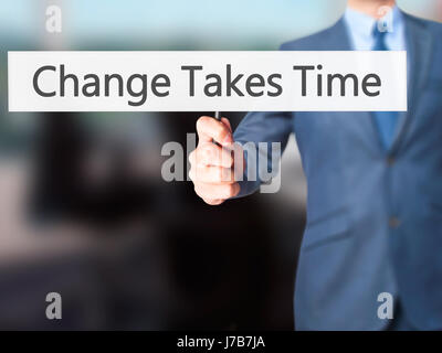 Le changement nécessite du temps - Businessman hand holding sign. Le commerce, la technologie, internet concept. Stock Photo Banque D'Images