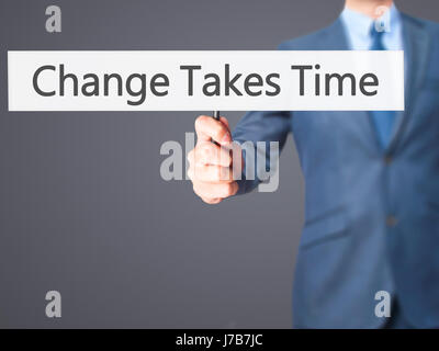 Le changement nécessite du temps - Businessman hand holding sign. Le commerce, la technologie, internet concept. Stock Photo Banque D'Images