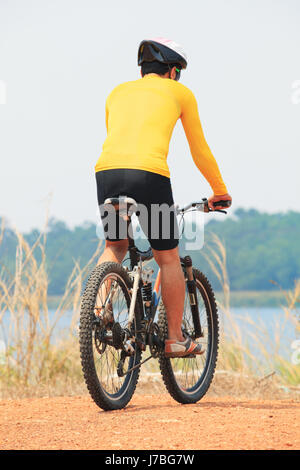 Vue arrière du jeune homme portant costume rider Vélo et casque de sécurité équitation vtt sur la masse de terre utiliser pour l'homme et passe-temps activités mâle Banque D'Images