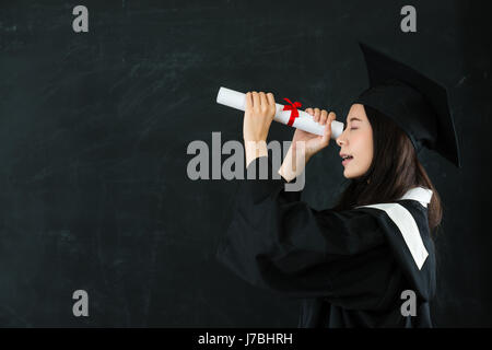 Les jeunes professionnels grad à diplôme intermédiaire comme un télescope regardez black copyspace. femme diplômée mains tiennent spyglass papier dans les vêtements. Banque D'Images