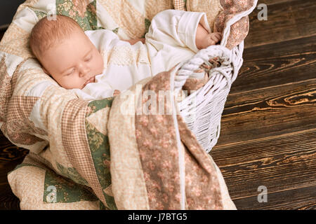 Caucasien enfant à dormir. Panier avec bébé, le bois l'arrière-plan. Bonne nuit dormez bien. Banque D'Images