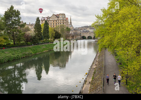 Bath, Angleterre - Avril 2017 : Pulteney Bridge traversant la rivière Avon à Bath, Angleterre, Royaume-Uni. Trois femmes d'exécution sur le sentier le long de la rivière et Banque D'Images