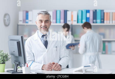 Sourire confiant médecin à la réception, le personnel médical travaillant sur l'arrière-plan Banque D'Images