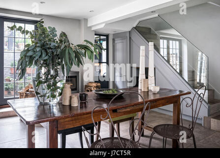 Vintage metal chaises et d'une paire de Philippe Hurel tabourets autour d'une table en bois dans le quartier chic de cuisine avec poêle à bois Banque D'Images