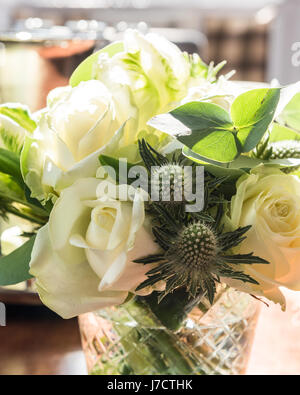 Un posey de roses blanches et de chardons en vase en verre Banque D'Images