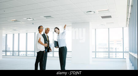 Homme d'montrant de nouveaux espaces de bureaux aux clients. Les gens d'affaires et de discuter à nouveau avec le bureau au courtier immobilier. Banque D'Images