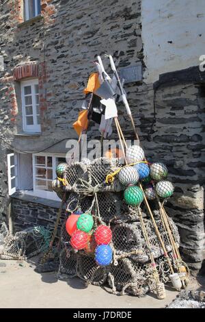 Des casiers à homard, des bouées et des drapeaux de marqueur à côté d'une maison en pierre dans un port de pêche traditionnel anglais Banque D'Images