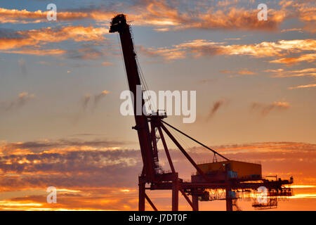 Un coucher de soleil, se découpant sur une grue à conteneurs à quai au port de Fremantle, Australie occidentale. Banque D'Images