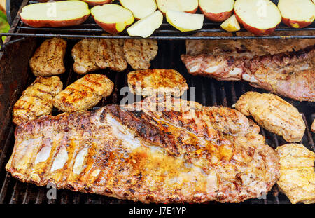 Bifteck de côte de porc sur la grille chaude du barbecue avec des flammes à l'arrière-plan, Close Up Banque D'Images