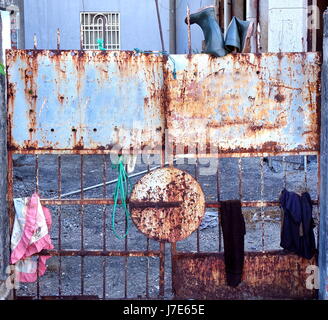 Une vieille porte en fer rouillé d'une maison déserte avec des morceaux de vêtements s'accrochent à lui Banque D'Images