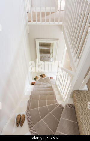 Meubles pour chaussures sur escalier peint avec Roger Oates stair runner. L'escalier et bannister sont peints dans des biens immobiliers par pointage Farrow & Ball Banque D'Images