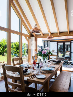 Chêne-pans voûtée, salle à manger avec de grandes baies vitrées. La table et les chaises sont de John Lewis et le coolicon insustrial pendentif cuivre ligh Banque D'Images