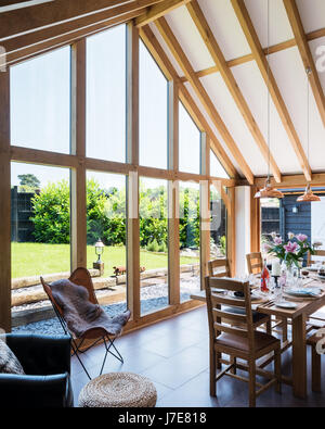 Chêne-pans voûtée, salle à manger avec de grandes baies vitrées. La table et les chaises sont de John Lewis et le coolicon insustrial pendentif cuivre ligh Banque D'Images