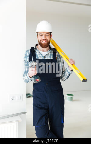 Les jeunes phoques barbus builder perceuse hoding et règle tout en effectuant la réparation Banque D'Images