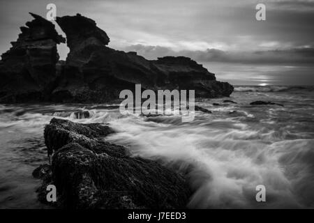 Une image en noir et blanc de forme inhabituelle de la pile de la mer au large des côtes de l'Indonésie Balinais avec un effet de l'exposition Création de mouvement de l'onde Banque D'Images