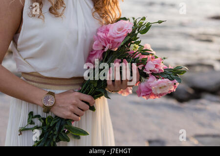 Woman holding bouquet of pink eustoma avec mer en arrière-plan flou Banque D'Images