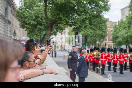 Le Cénotaphe, Whitehall, Londres UK. 24 mai 2017.Journée internationale des Casques bleus des Nations Unies Cérémonie du Souvenir a lieu à 13h dans la région de Whitehall au milieu d'une sécurité optimale. La bande du Welsh Guards et le Color Guard de l'Organisation des Nations Unies responsable de l'Association des anciens membres du corps diplomatique et d'autres couches de la couronne Royal United Services Institute. London District GSM Andrew 'Vern' Stokes, Coldstream Guards, il surveille la cérémonie (centre) avec les touristes regardent à la gauche. Credit : Malcolm Park editorial/Alamy Live News. Banque D'Images