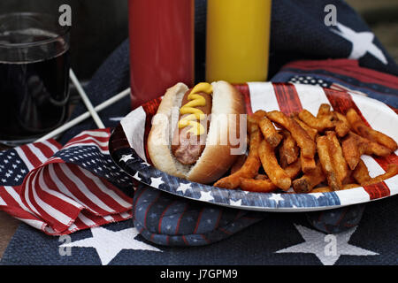 Hot dog avec de la moutarde à un pique-nique barbecue du 4 juillet. L'extrême profondeur de champ avec accent sur les saucisses. Banque D'Images