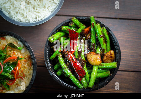 Un bol de riz bouilli avec des pois et de porc sur une table en bois Banque D'Images